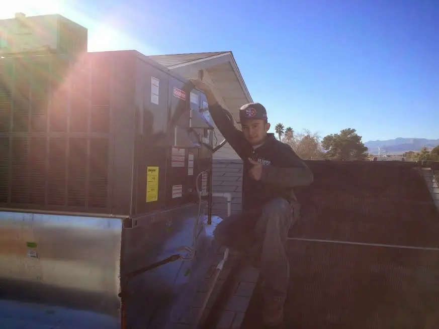 HVAC technician performing Heat Pump Repair on a rooftop unit in Geneseo